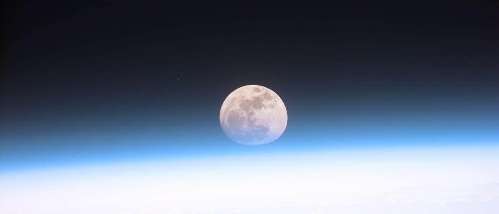 Dünya atmosferinin ardından görünen dolunay (NASA)
